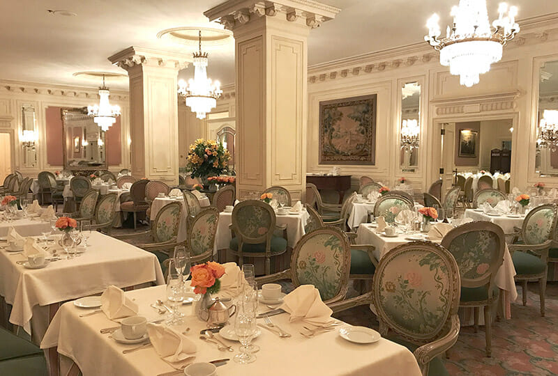 Le Fontainebleau Dining Room set with tables and floral chairs.