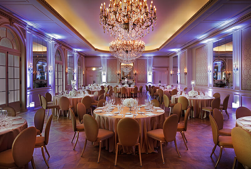 Versailles ballroom at night with gold tablecloths and purple uplights