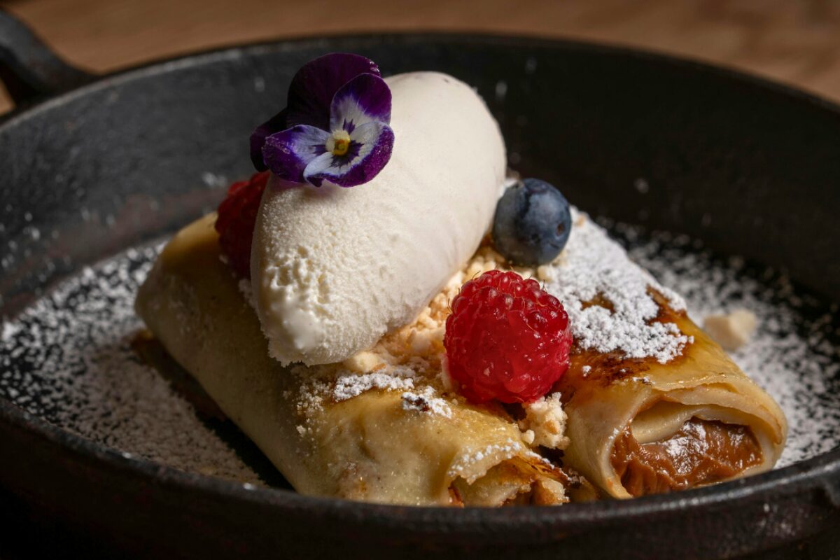 Close up of crepe with raspberry and flower garnish