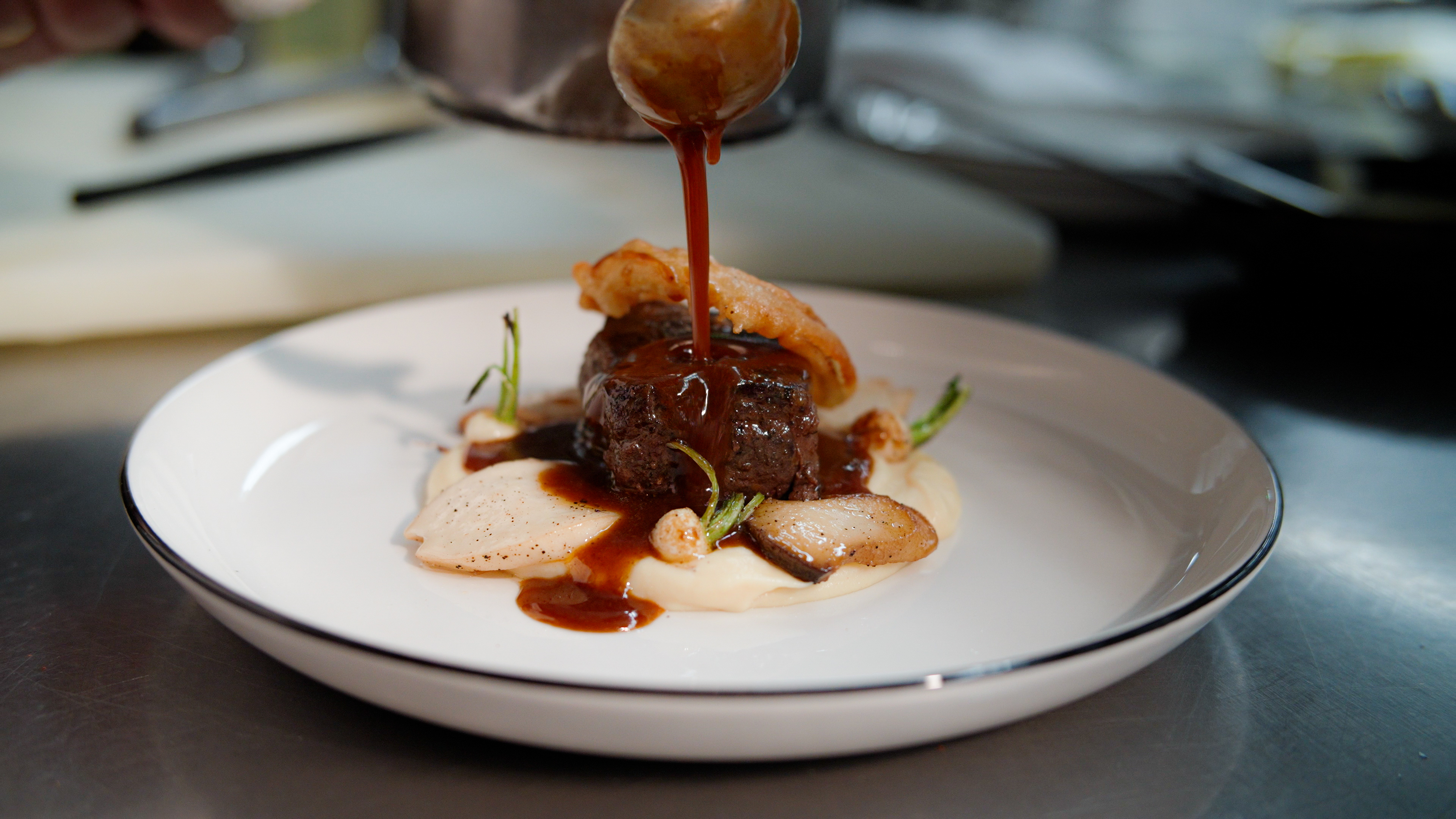 A plate being finished and garnished by a chef.